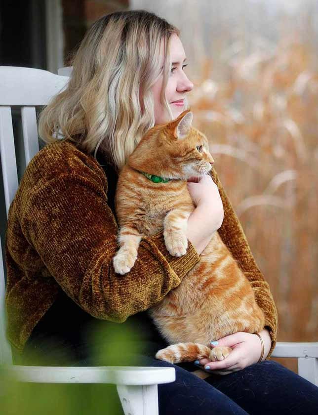 Woman sitting on porch with ginger cat